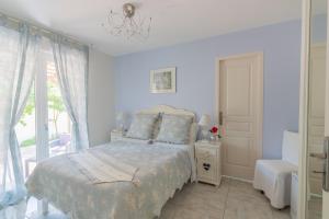 a white bedroom with a bed and a window at La Villa de l'Olivier in Cap d'Agde