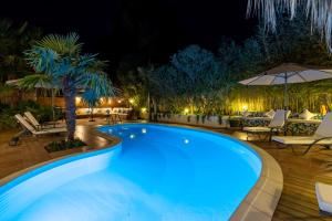 a swimming pool at night with tables and chairs at La Villa de l'Olivier in Cap d'Agde