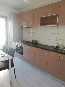 a kitchen with brown cabinets and a table and a stove at Marlen’s Apartment in Bucharest
