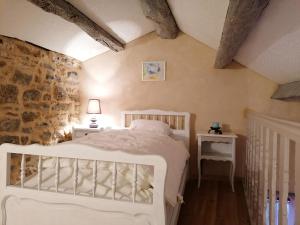 a bedroom with a white bed and a stone wall at La Maison Huguétoune in Nant