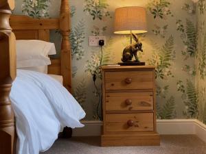 um quarto com uma cama e um candeeiro numa cómoda em Lancasters Cottage em Horsham