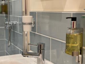 a bathroom sink with a soap dispenser next to a mirror at Lancasters Cottage in Horsham