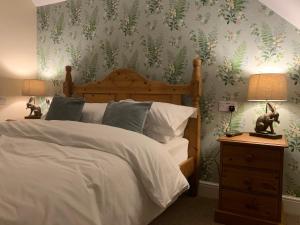 - une chambre dotée d'un lit avec des feuilles vertes sur le mur dans l'établissement Lancasters Cottage, à Horsham