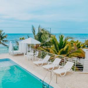 a pool with chairs and an umbrella and the ocean at Hotel Green Coveñas in Coveñas