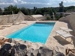 a swimming pool in a stone wall with two lounge chairs at TRULLI TESORO in Cisternino