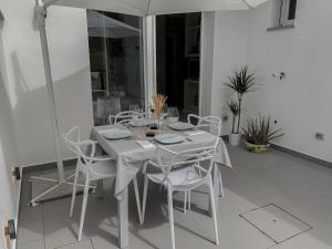 a white table with white chairs and an umbrella at Villa Luminosa in Torre del Lago Puccini