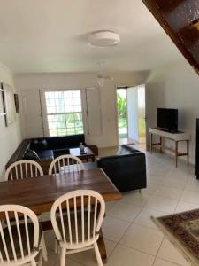a living room with a wooden table and chairs at Casa com 3 suítes - À 150m da praia de Geribá in Búzios