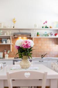 un vaso pieno di fiori rosa e bianchi su un tavolo di Confortevole appartamento provenzale a SantʼAntìoco