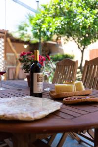 una bottiglia di vino e formaggio su un tavolo di legno di Confortevole appartamento provenzale a SantʼAntìoco