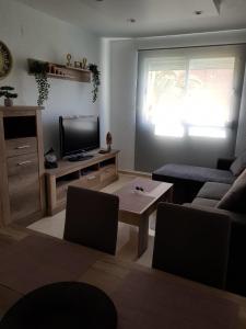 ein Wohnzimmer mit einem Sofa und einem TV in der Unterkunft HR PARADISE PARQUE RESIDENCIAL in Benidorm