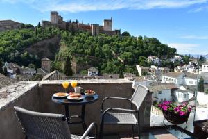 a table with food on a balcony with a castle at Apartamentos Alhambra in Granada