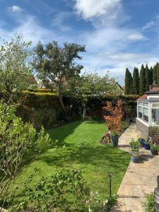 un patio con césped verde y árboles y una casa en The Garden Suite en Harrogate