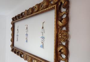 een sierlijk gouden fotoframe met oorbellen erin bij Cuscino e Cappuccino B&B in Alghero