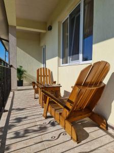 two wooden chairs sitting on the porch of a house at Vila alex in Mangalia