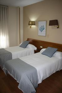a hotel room with two beds with blue and white sheets at Hotel Los Robles in Cangas de Onís