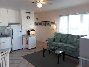 a living room with a green couch and a kitchen at Sandpeddler Inn and Suites in Wrightsville Beach