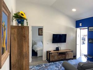 uma sala de estar com televisão e um quarto com cama em Casa do Chinelo Azul em Queluz