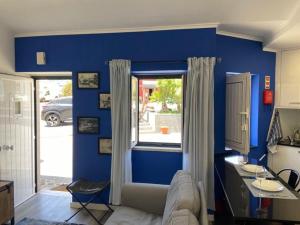 een blauwe woonkamer met een bank en een raam bij Casa do Chinelo Azul in Queluz