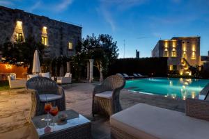 a patio with a table and chairs next to a pool at Palazzo Ducale Venturi - Luxury Hotel & Wellness in Minervino di Lecce
