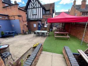 Un patio con una mesa y una sombrilla roja. en The Plough Inn Wigston, en Wigston Magna