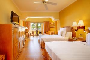 a hotel room with two beds and a television at Barceló Maya Colonial - All Inclusive in Xpu Ha
