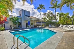 a swimming pool in front of a house with palm trees at Big Island Condo with Pool Access 1 Mi to Beach! in Kailua-Kona