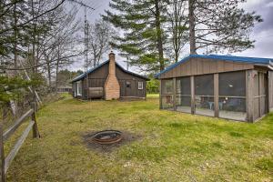 una pequeña casa en medio de un patio en Rustic River View Cabin with Fire Pit, Games and Grill en Houghton Lake