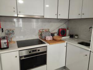 a kitchen with white cabinets and a stove top oven at Flamingo in Sesimbra