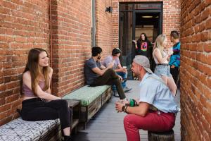 a group of people sitting on benches against a brick wall at Hostel Fish in Denver