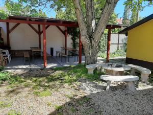 a picnic shelter with benches and a tree at Gyopár Gyöngye Apartmanház in Orosháza