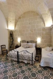1 Schlafzimmer mit 2 Betten und einer Steinmauer in der Unterkunft Le 3 Volte in Cursi