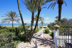 a walkway with palm trees and the beach at 030 Villa Marines - Deniasol in Denia