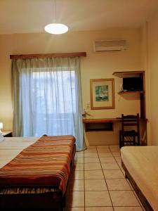 a bedroom with a bed and a window with a desk at Pension Irene in Sougia