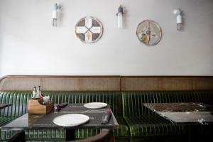 un banco verde con dos platos en una mesa en Hotel Botanica en Belgrado