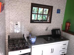 uma cozinha com um fogão, um lavatório e uma janela em Chalé da Ana Aventureiro em Angra dos Reis