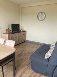 a living room with a blue couch and a clock on the wall at F2 Vire centre in Vire +7 photos