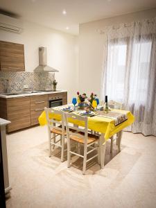 a kitchen with a dining table with yellow table cloth at Talos Apartments in San Vito lo Capo