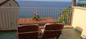 una mesa de madera y sillas en un balcón con vistas al océano en Casa Vacanza sul Mare, en Cefalú