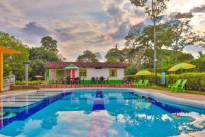 a swimming pool in front of a house at Hotel Campestre Pueblo Bello in Armenia