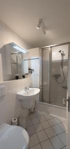 a white bathroom with a shower and a sink at Südwäldchen in Westerland (Sylt)