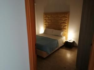 a small bedroom with a bed with a headboard at Zibibbo Beach Apartments - Trapani in Trapani