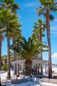 a resort with palm trees and chairs on the beach at Tridente Mare Apart Hotel in Pefkohori
