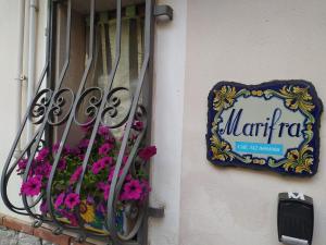 una señal en el lado de una ventana con flores en Marifra Flats, en Taormina