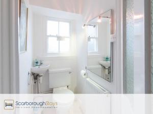 a bathroom with a toilet and a sink and a mirror at Scarborough Central Townhouse in Scarborough