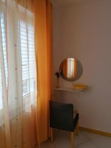 a mirror and a chair in a room with a window at Big Blue - Xenija (Veliko Plavetnilo - Ksenija) in Metajna