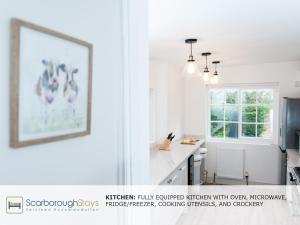 a white kitchen with a picture of chickens on the wall at Scarborough Central Townhouse in Scarborough