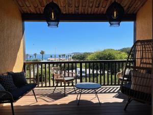 - une terrasse couverte avec des chaises et une table sur un balcon dans l'établissement Appartement neuf climatisé - vue mer Saint-Tropez - 50m plage et port - piscine, à Gassin