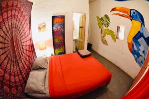 a bedroom with an orange bed and a wall with paintings at Hostal La Casa de Juan in Valle de Anton