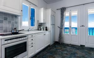 une cuisine avec des placards blancs et une vue sur l'océan. dans l'établissement Aphrodite by Akroploro, à Pollonia