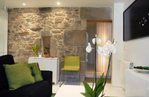 sala de estar con pared de piedra y silla amarilla en Green Home, en Santiago de Compostela